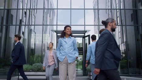 smiling business lady standing feeling confident outdoors modern glass building.