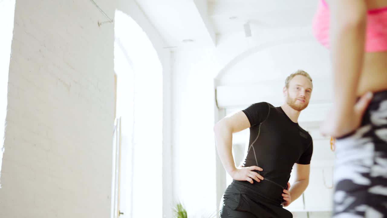 남자 피트니스 강사와 젊은 여성 고객들이 체육관에서 운동하기 전에 몸을 따뜻하게 하기 위해 지 서클 운동을 하는 사진입니다.