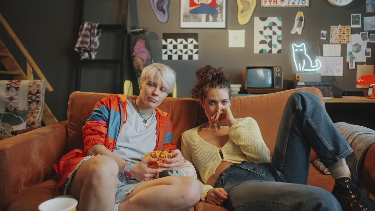 Young Female Friends Watching Tense Sports Game on TV with Disappointment