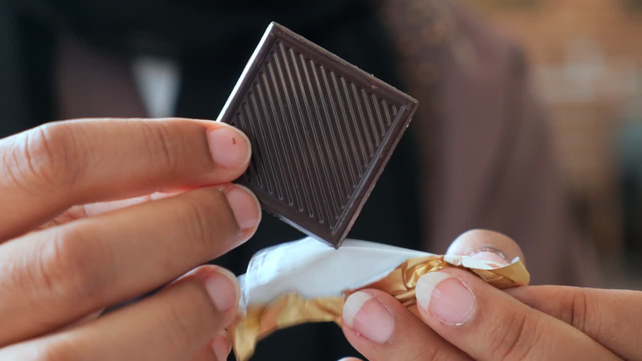 una mujer comiendo chocolate oscuro.