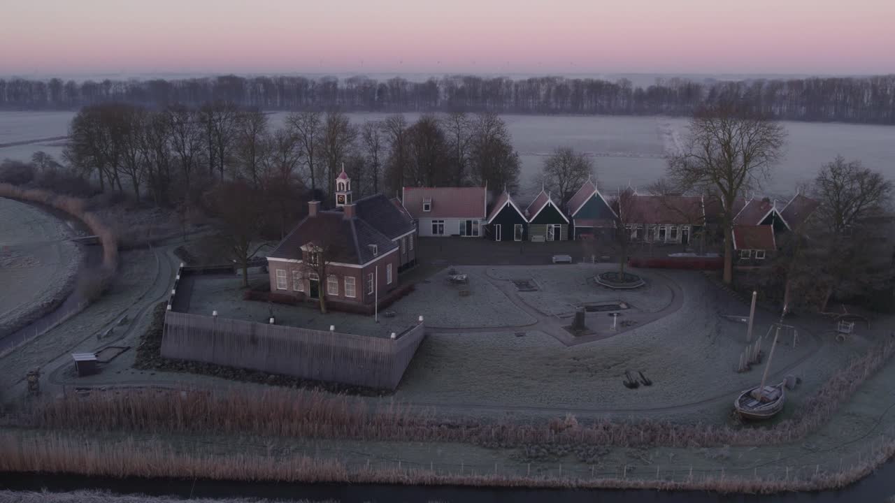 Luftfoto af landsby med kirke og træer under gylden solopgang, Schokland