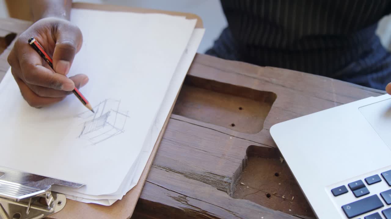 carpintero dibujando un boceto en papel mientras usa una computadora portátil 4k