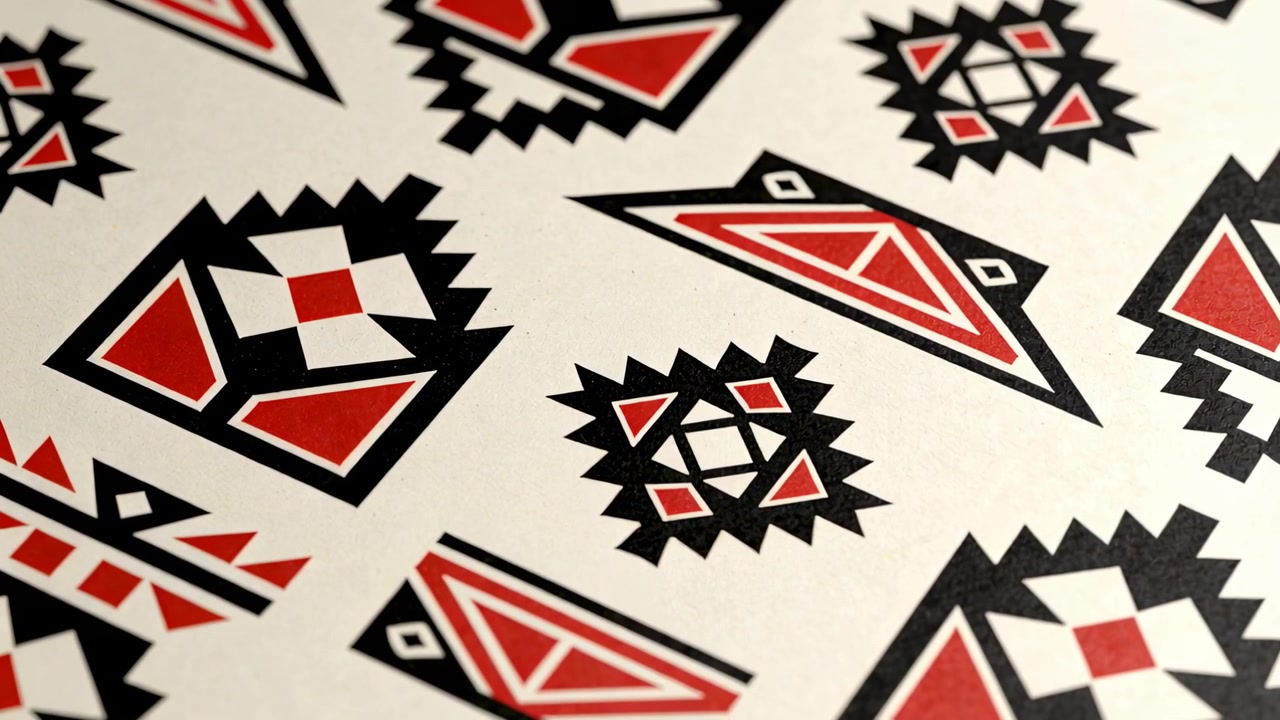 Shifting camera capturing printed sheet on studio table, emphasizing central black red motifs