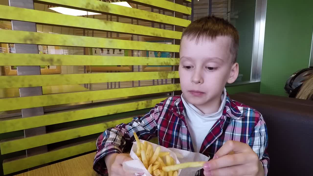 Bambino che mangia patatine fritte al bar. Bambini in un ristorante fast food che mangiano patatine fritte.
