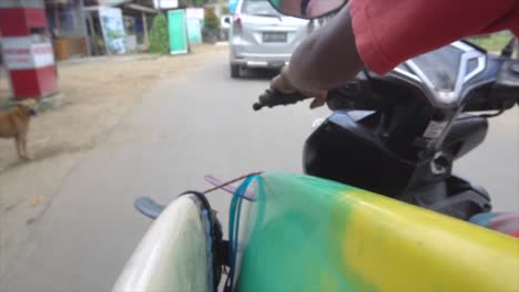 tablas de surf en cámara lenta cuelgan del borde de la motocicleta en indonesia