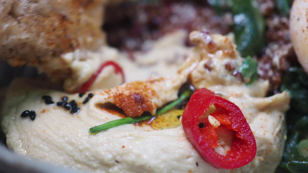 Intingere il pane nell'hummus cremoso guarnito con peperoncino.