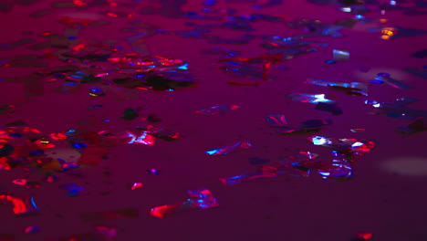 close up of sparkling confetti on floor of nightclub bar or disco with flashing strobe lighting