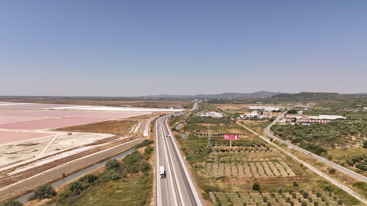 Highway road with cars driving through close to the salt ponds producing salt