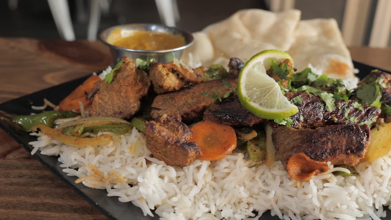 kebab tandoori chapado tradicional con bistec de verduras sobre arroz basmati con naan, control deslizante de cámara lenta de cerca 4k