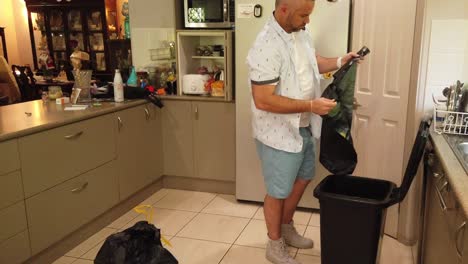 man putting new bin liner in garbage bin after emptying the old one