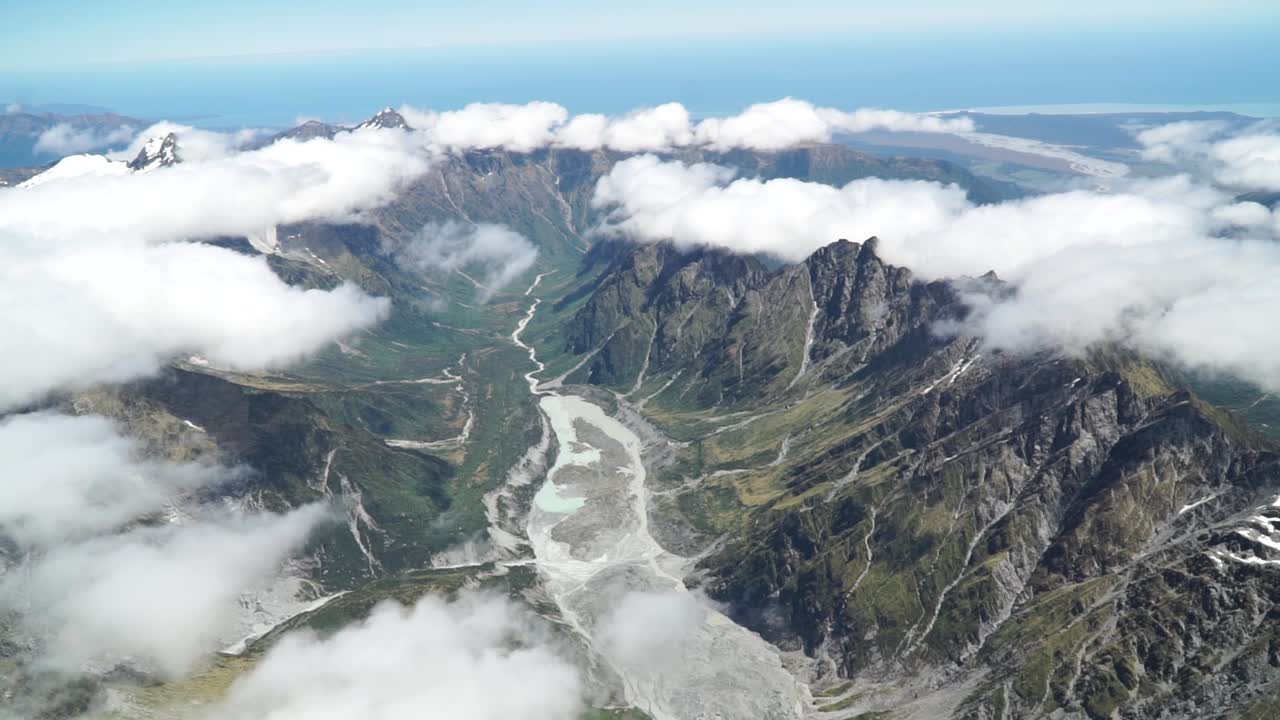 съемка с самолета над западным побережьем ледника франца-иосифа, национального парка аораки маунт-кук с облаками, заснеженными скалистыми горами и океаном на заднем плане