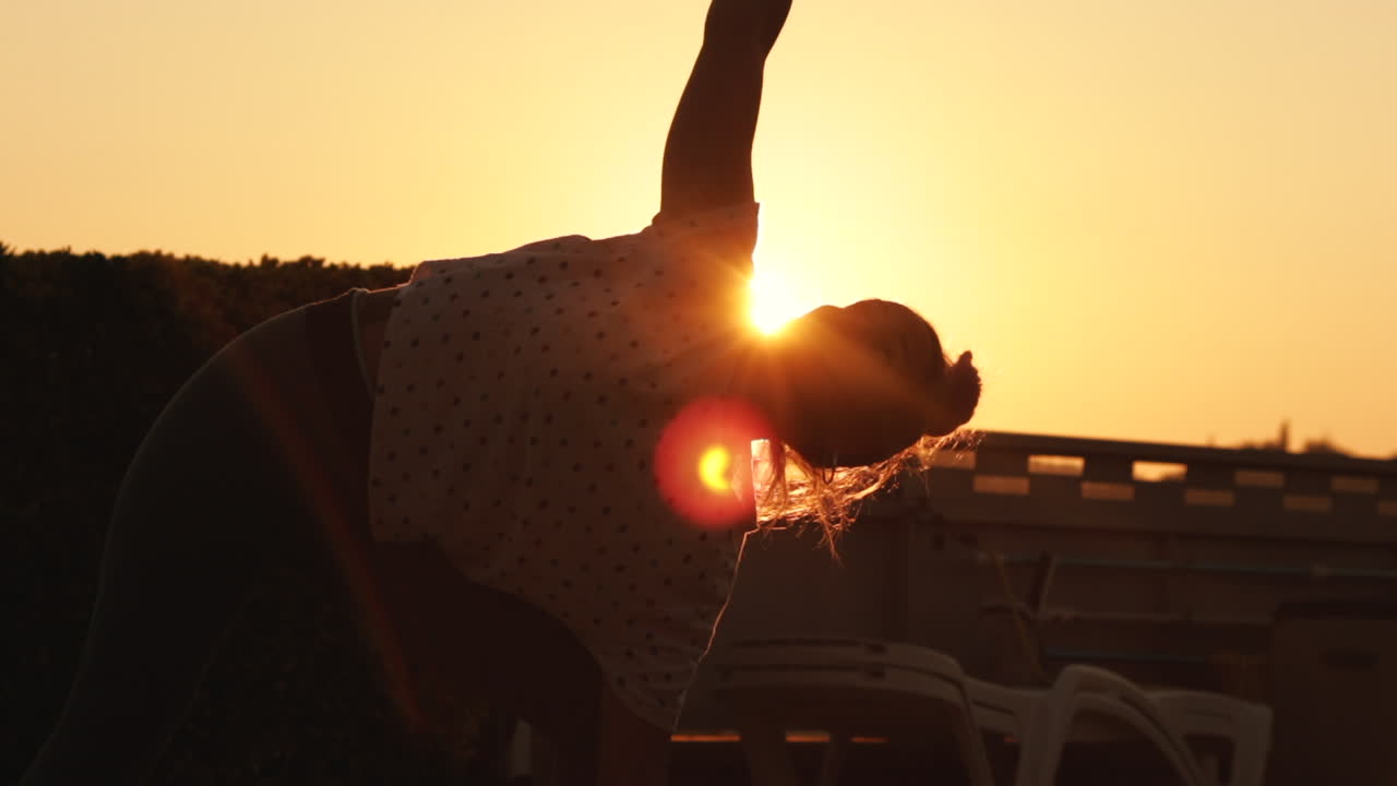 Smooth traveling of how the sun appears behind a young woman while doing yoga pose at sunrise with a strong sun backlight