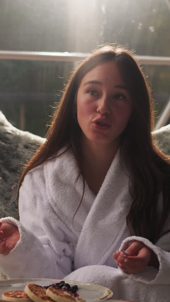 Woman tells story to man holding cutlery in hands. Lady stops eating for conversation with husband during breakfast. Time on round glamping house terrace