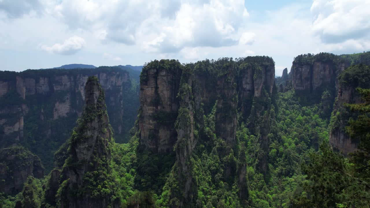drone volando hacia la imponente montaña aleluya en el exuberante parque forestal nacional de zhangjiajie, china