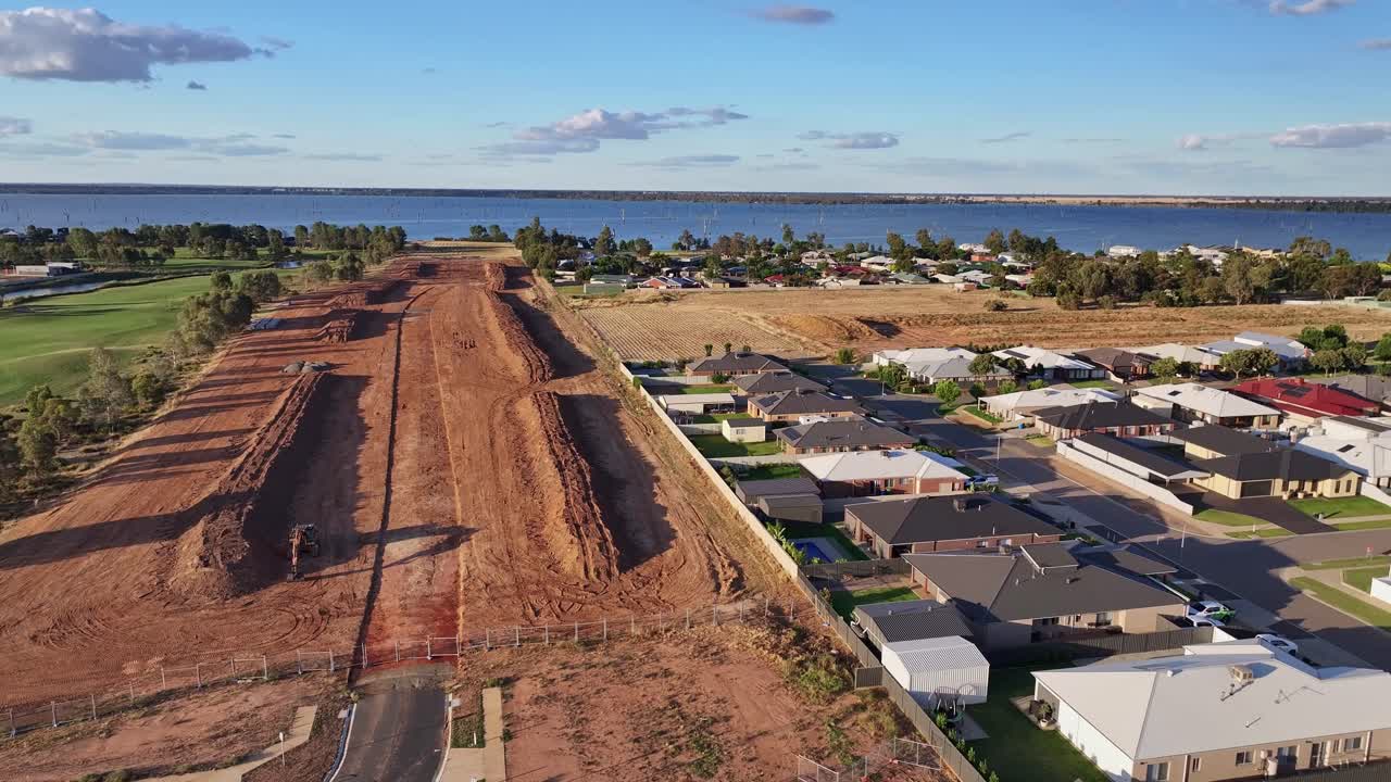 descenso aéreo sobre el sitio de construcción de una nueva casa con el campo de golf black bull y el lago mulwala más allá