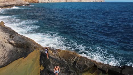 vista aérea de unos amigos disfrutando de unas piscinas naturales en una formación geológica en la costa de ibiza