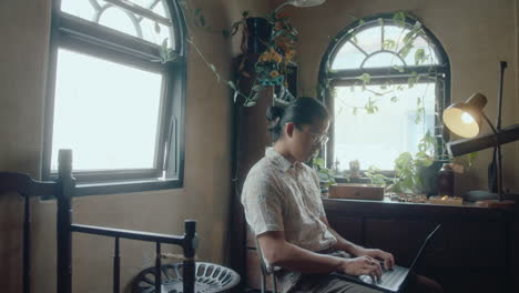 young asian man working with laptop in antiques store