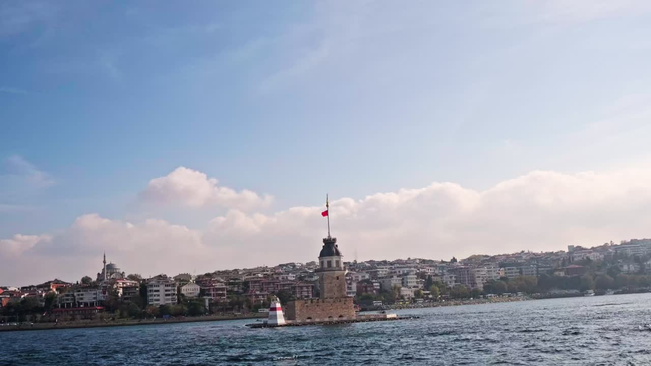 High-quality 4K footage capturing the beauty of the Maiden's Tower surrounded by the blue waters of the Bosphorus. The background features the urban coastline of Uskudar and distant city silhouette