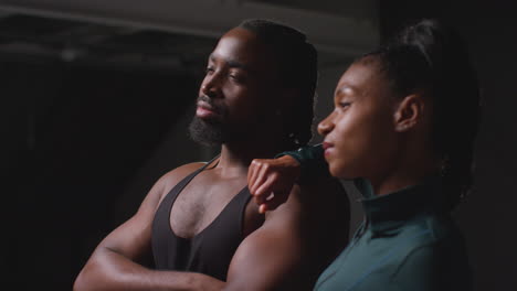 studio portrait of smiling athletic couple or friends in fitness clothing training shot in gym with low key lighting 4