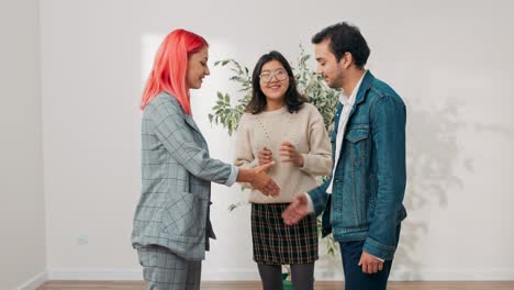 reunión con el agente inmobiliario propietario del apartamento pareja joven en busca de apartamento para alquilar comprar en el centro de la ciudad visita para hablar con el asesor asegurador inspección de la casa mujeres estrechan la mano en saludo