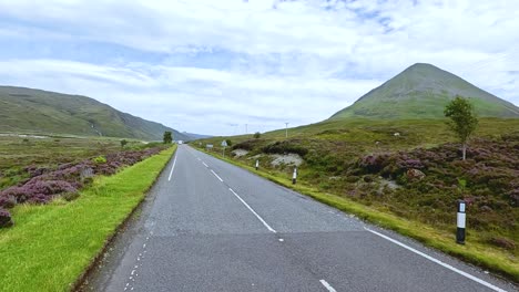 forward-facing camera captures a smooth drive on a rural road through green hills and heather under soft daylight on the isle of skye