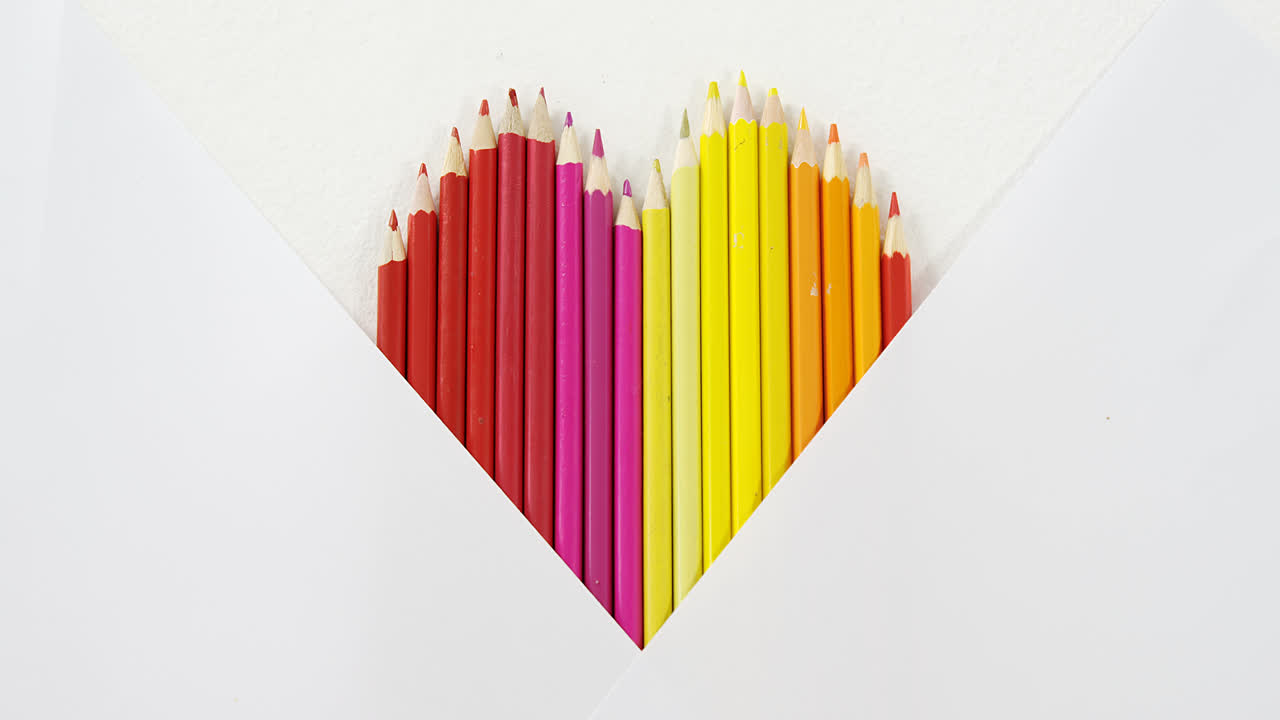 lápices de colores dispuestos en forma de corazón sobre un fondo blanco