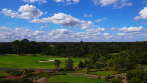 Aerial-view-of-Golfers-teeing-off-onto-golf-course-fairway-under-beautiful-blue-sky