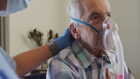 video de una doctora biracial con máscara facial manteniendo oxígeno a un anciano caucásico
