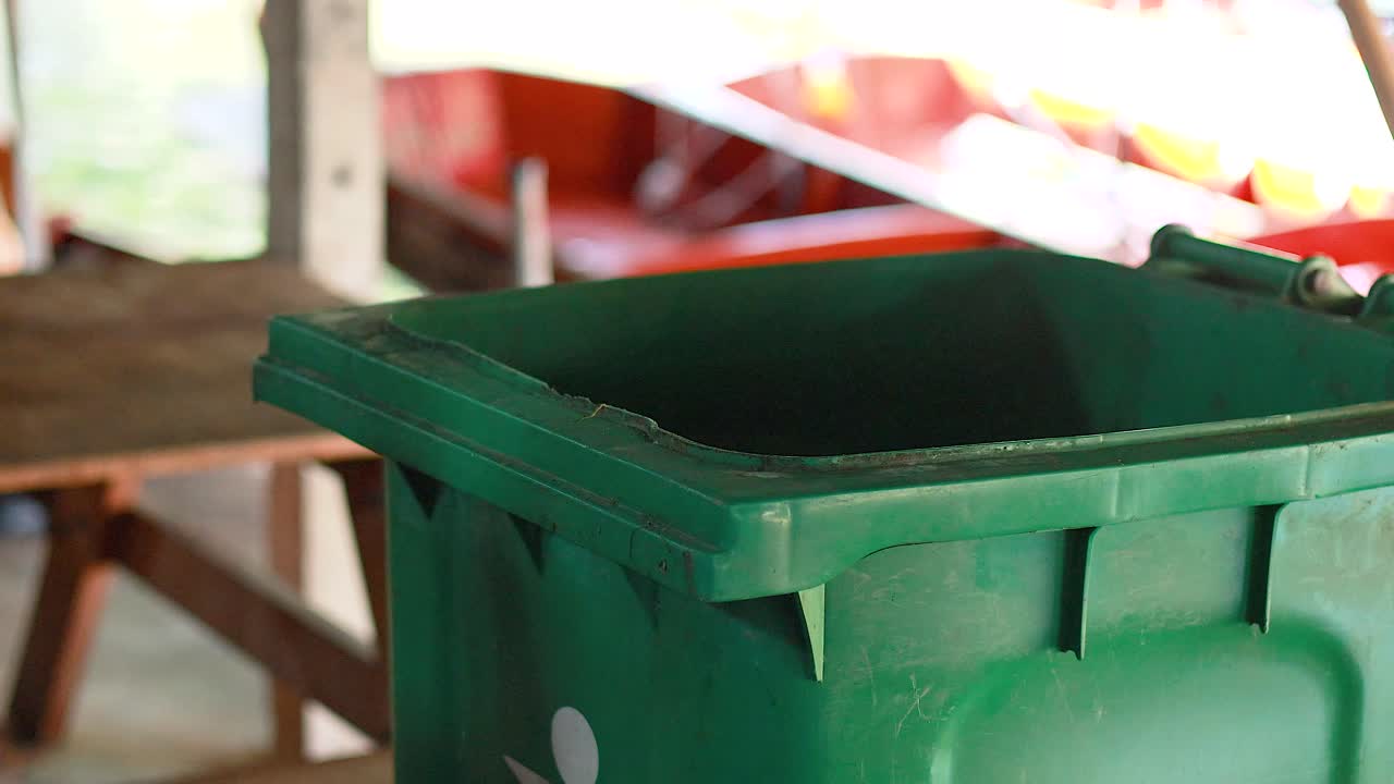 Throwing trash into a green bin in Bangkok
