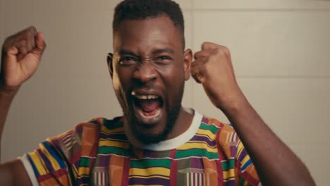 Portrait-Of-African-American-Man-Wearing-Kente-Fabric-Cloth-Jumping-And-Celebrating