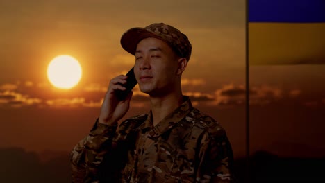 soldado en llamada telefónica al atardecer con bandera ucraniana