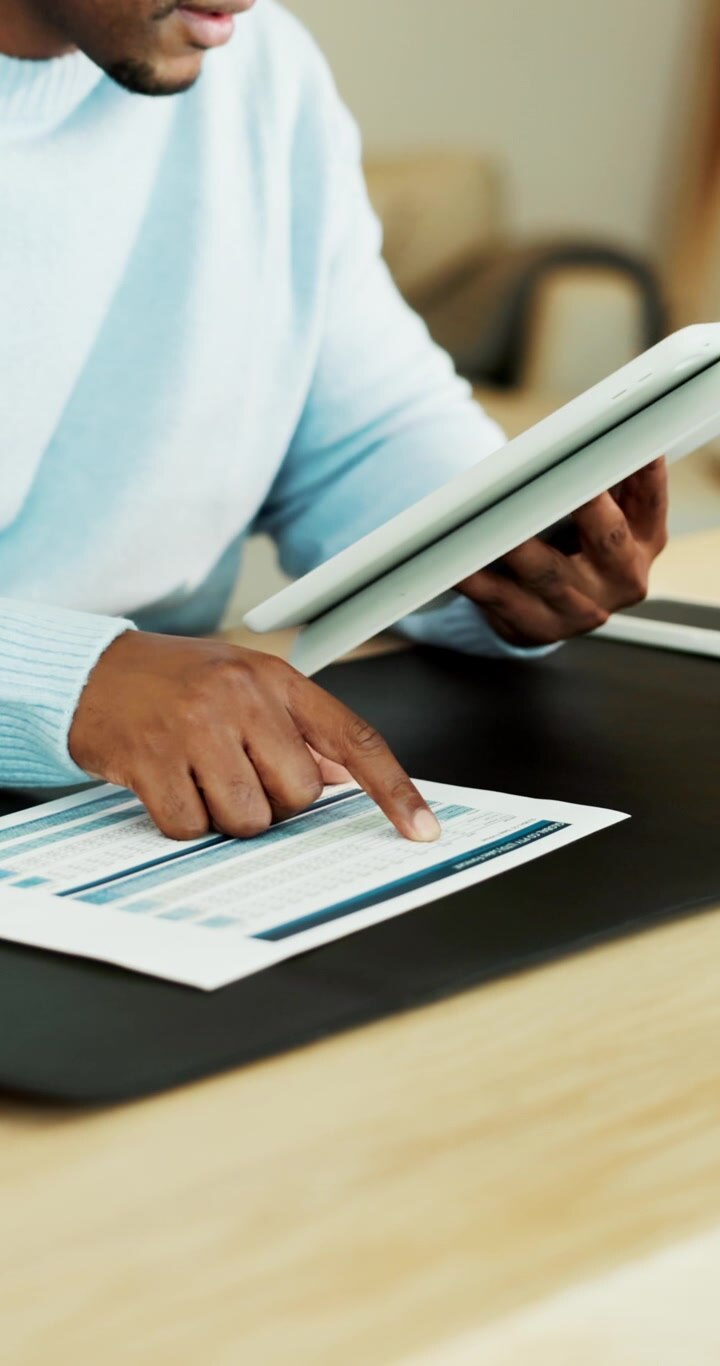 Professional Reviewing Financial Data on Paper and Tablet