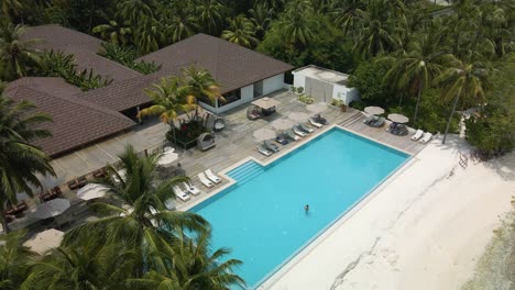 Girl-in-the-pool-in-a-hotel-complex-surrounded-by-green-palm-trees-in-the-Maldives