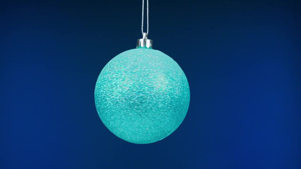 Funkelnde türkise Weihnachtskugel auf blauem Hintergrund