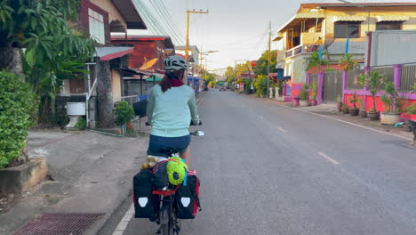 Una-Filmación-Dinámica-De-Una-Mujer-Que-Viaja-En-Bicicleta-Con-Alforjas-Y-Comestibles-En-La-Parte-Trasera