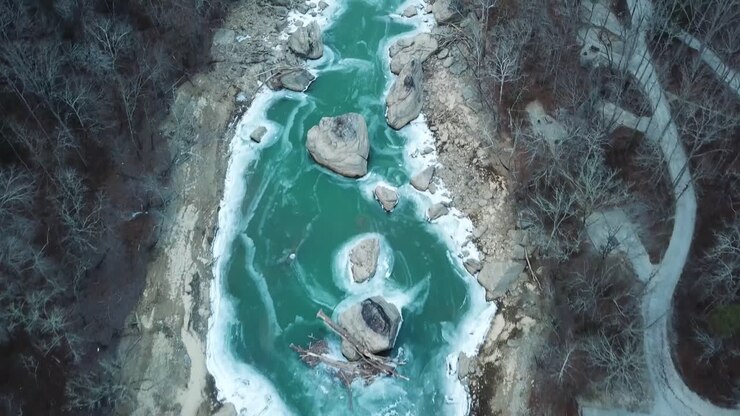 Legno galleggiante e massi in un fiume di montagna ghiacciato.