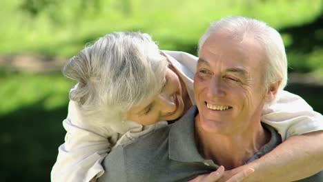 close up of a old woman hugging her husband sitting on a bench