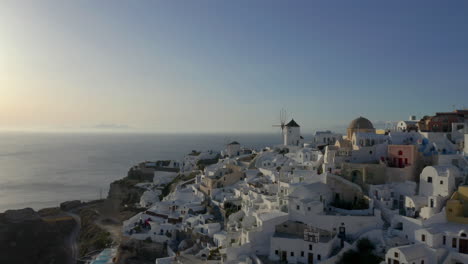 Toma-De-Drone-En-Línea-Recta-De-Oia-En-Santorini,-Grecia-Durante-La-Puesta-De-Sol