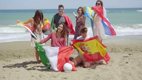 Grupo-De-Amigos-En-La-Playa-Con-Fútbol-Y-Banderas