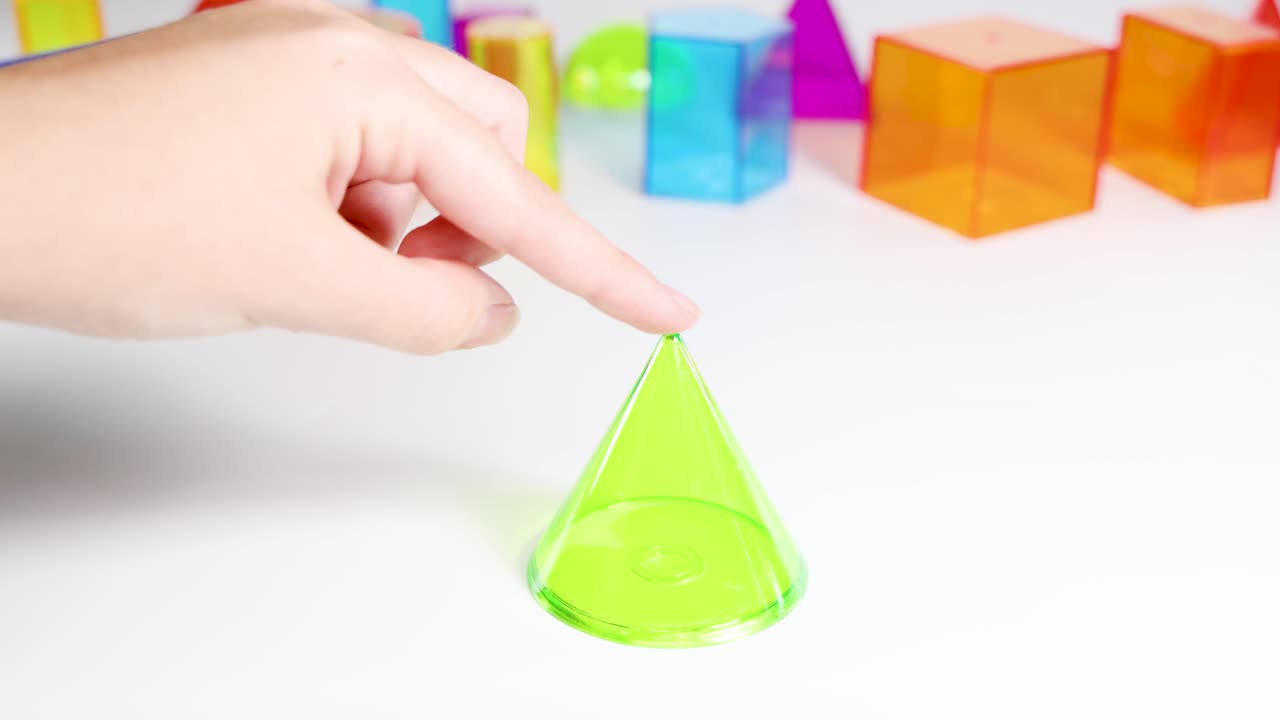 Hands manipulate vibrant 3D geometric shapes on a white surface, highlighting educational and playful interactions