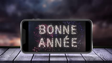 animation of bonne annee 2016 text and frieworks on smartphone screen in the background