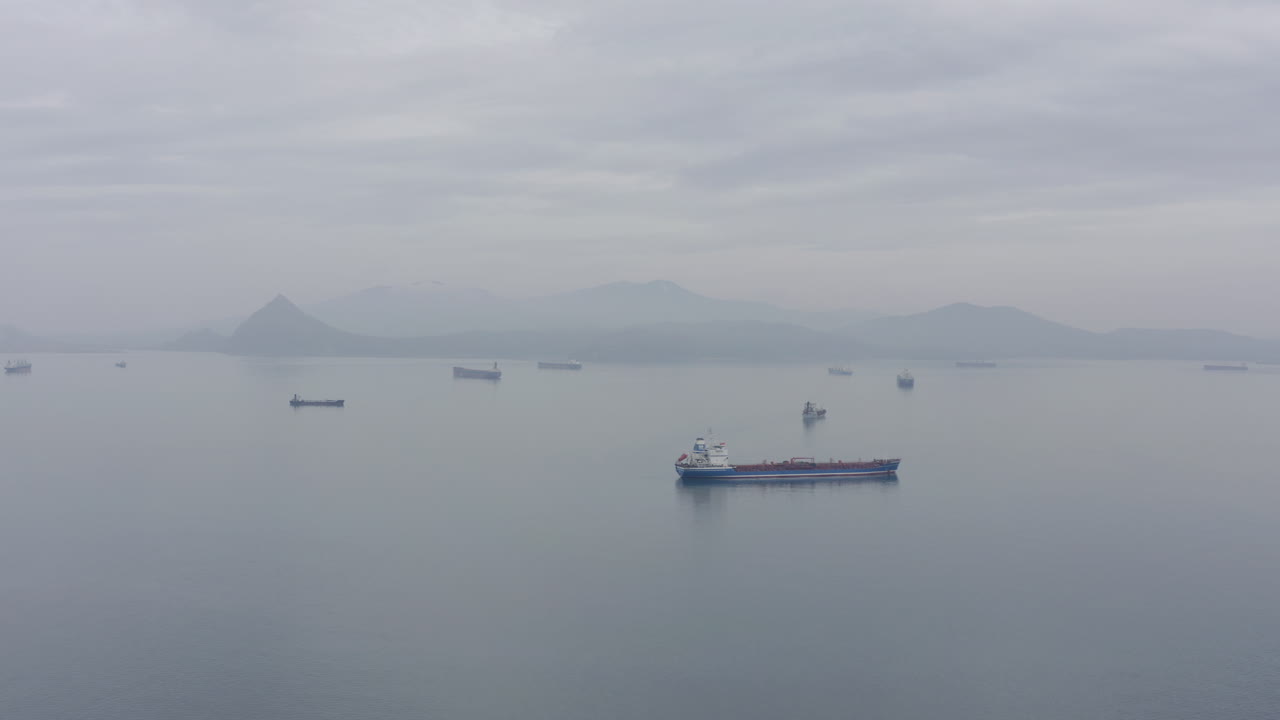 흐린 날 먼 거리에 산등성이가 있는 고요한 날씨에 정박지 대기 지역에 있는 배들