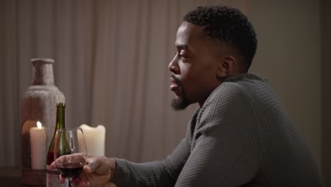 man drinking red wine at a table