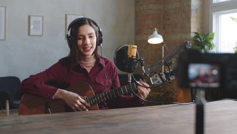 young female musician filming online guitar class in studio