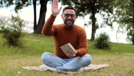 young man reading book on lawn