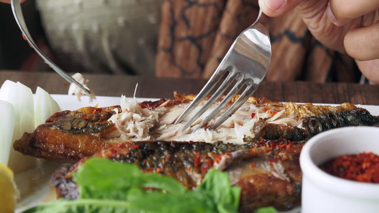 그릴 된 물고기를 먹는 사람