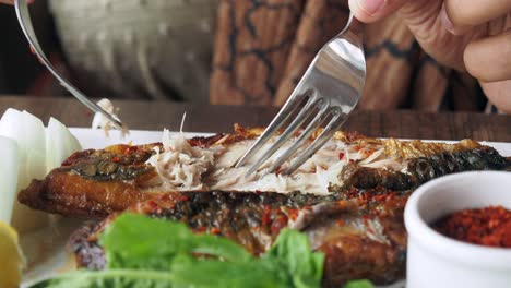 persona que come pescado a la parrilla