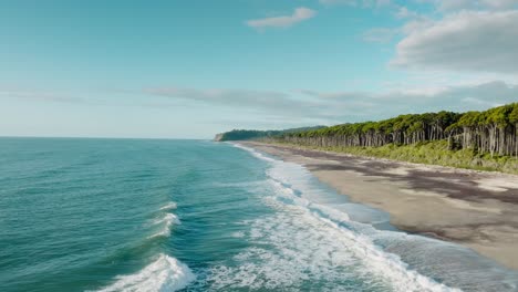 Fast-aerial-drone-flight-over-long-sandy-beach-of-remote-Bruce-Bay-and-the-Tasman-Sea-with-rolling-white-wash-waves-in-South-Westland,-New-Zealand-Aotearoa