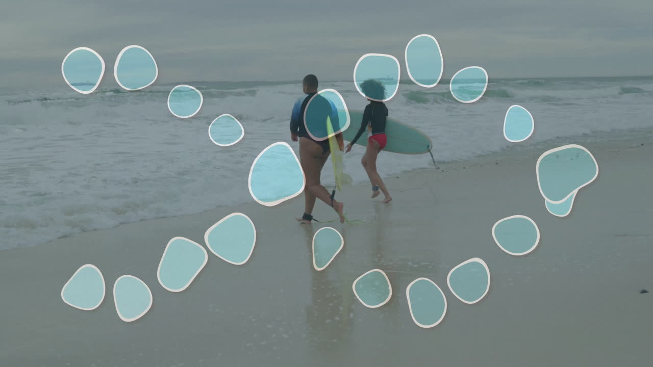 Two people carrying surfboards running into ocean with bubble animation overlay