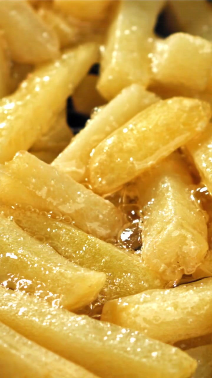 Patatine fritte dorate che friggono in olio bollente e gorgogliante